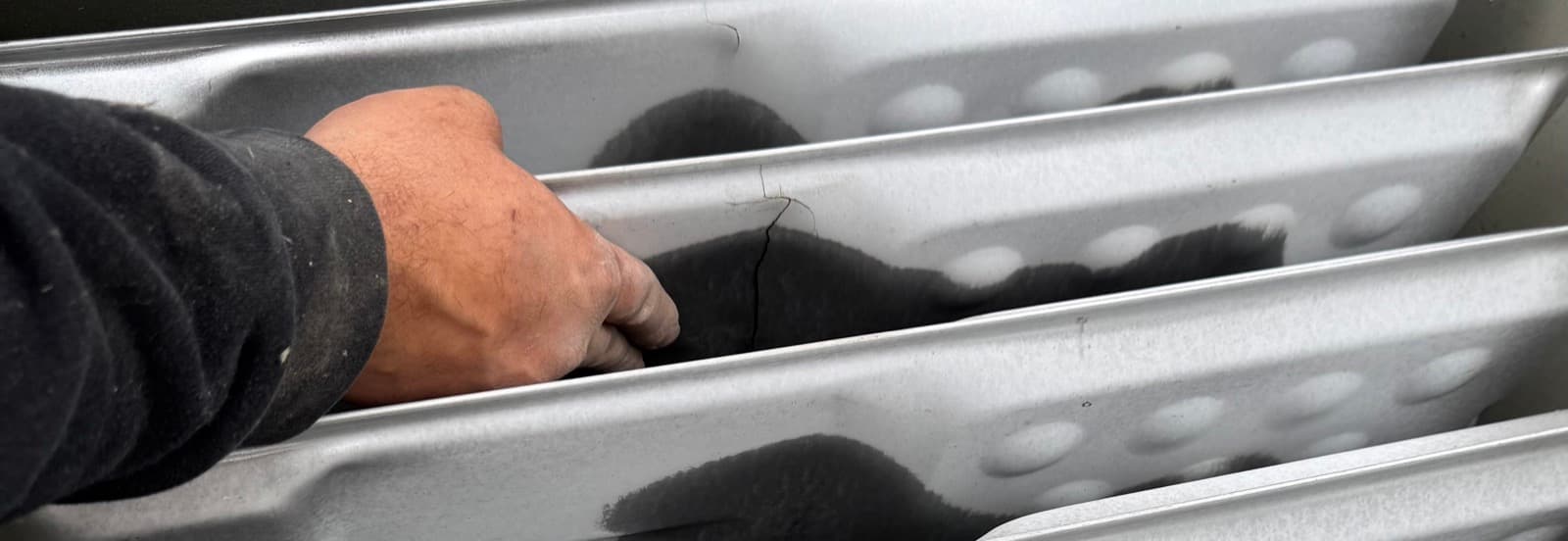 Cracked gas heater heat exchanger - visible crack in metal panel creates direct carbon monoxide leak pathway